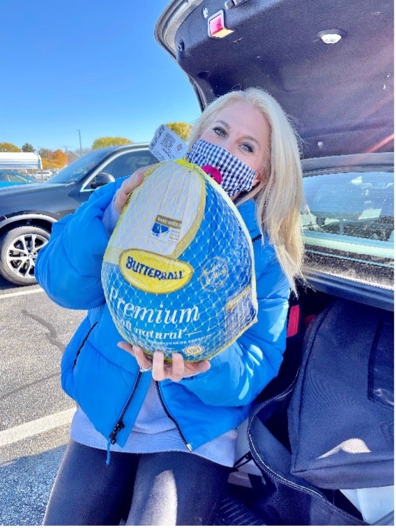 Woman loading frozen Butterball turkey into car trunk