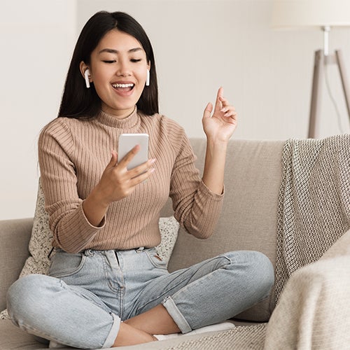 Girl listening to wireless headphones sitting on couch