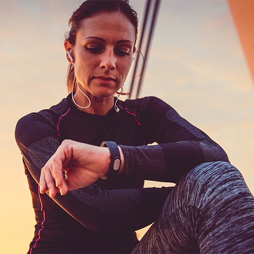 Woman exercising while listening to wireless headphones and checking smart watch